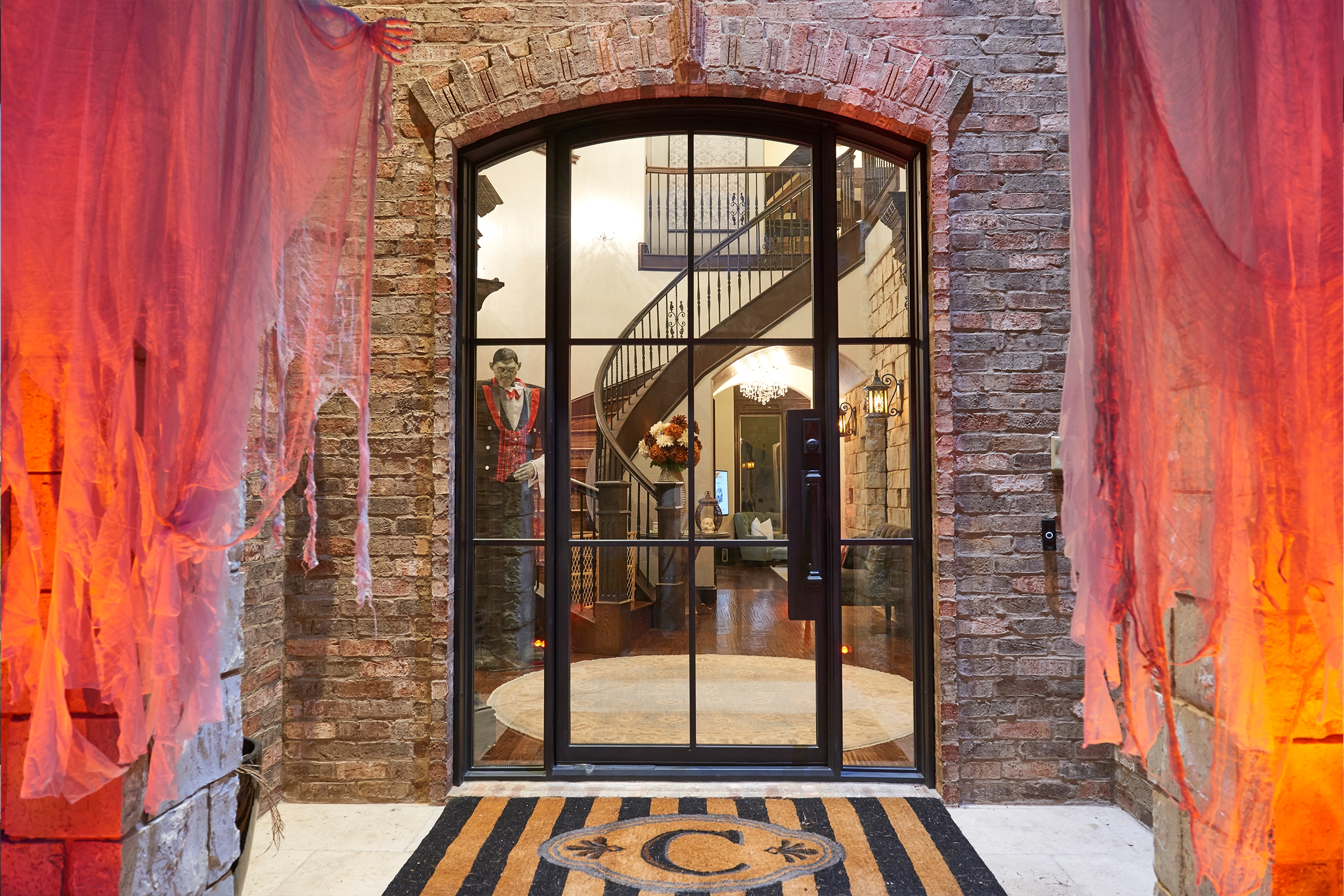 Halloween-decorated entrance with brick wall and glass door.